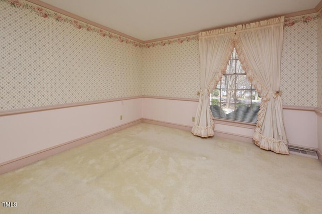 spare room with wallpapered walls, ornamental molding, carpet flooring, and wainscoting