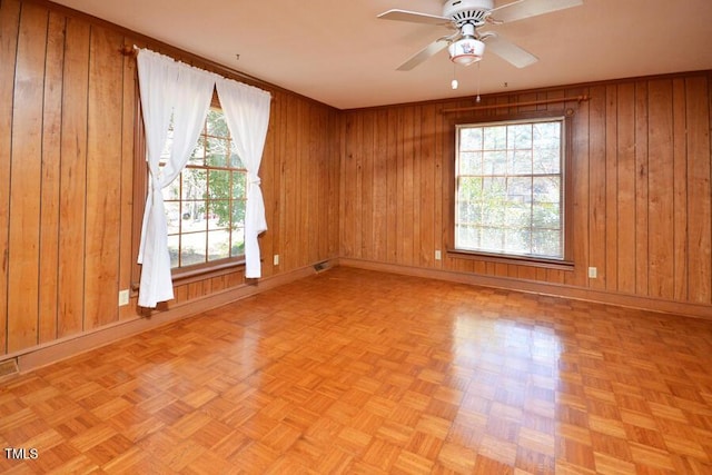 unfurnished room with wooden walls, baseboards, and ceiling fan