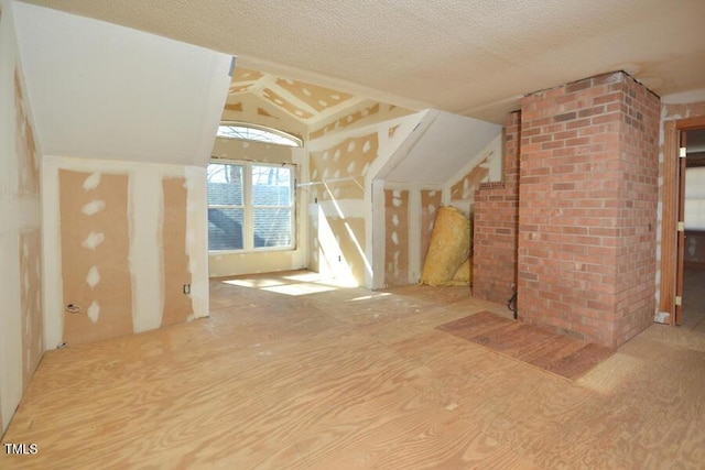 additional living space with lofted ceiling and a textured ceiling