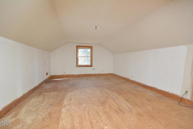 additional living space featuring lofted ceiling, baseboards, and light wood finished floors