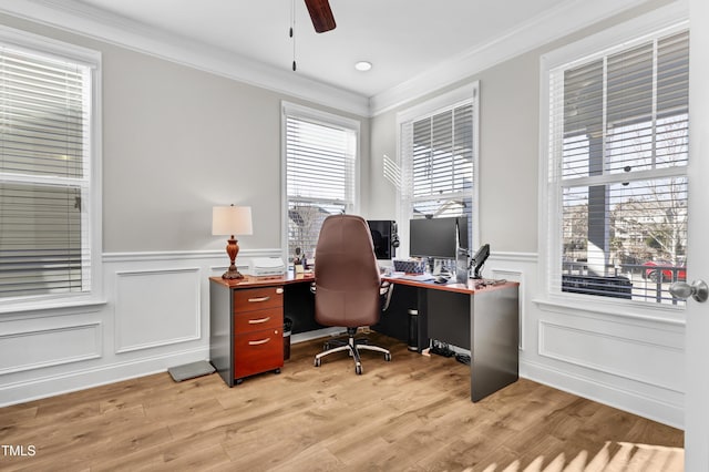 office space featuring crown molding, a ceiling fan, light wood-style floors, and wainscoting