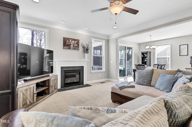 carpeted living room with baseboards, a fireplace with flush hearth, recessed lighting, crown molding, and ceiling fan with notable chandelier