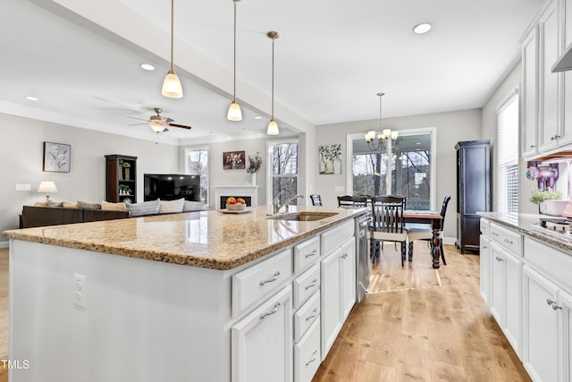 kitchen featuring a center island with sink, white cabinetry, a sink, light wood-style floors, and stainless steel dishwasher