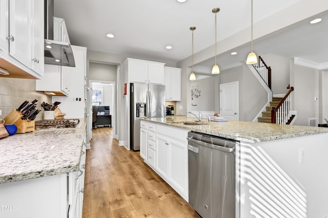 kitchen featuring light wood-style flooring, a sink, appliances with stainless steel finishes, white cabinetry, and backsplash