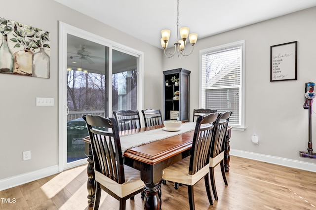 dining area featuring baseboards, light wood-style floors, and ceiling fan with notable chandelier