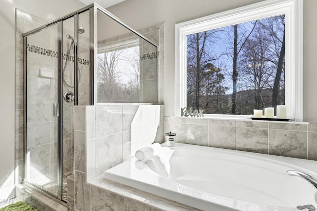 bathroom with plenty of natural light, a garden tub, and a shower stall