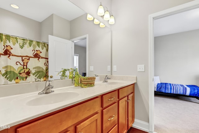 ensuite bathroom with double vanity, ensuite bath, baseboards, and a sink