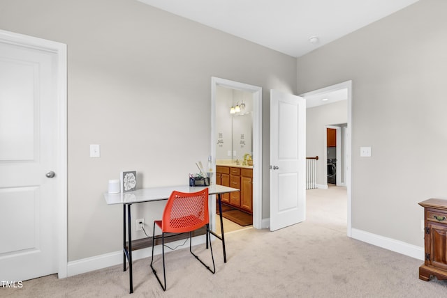 home office featuring light colored carpet, washer / clothes dryer, baseboards, and a sink