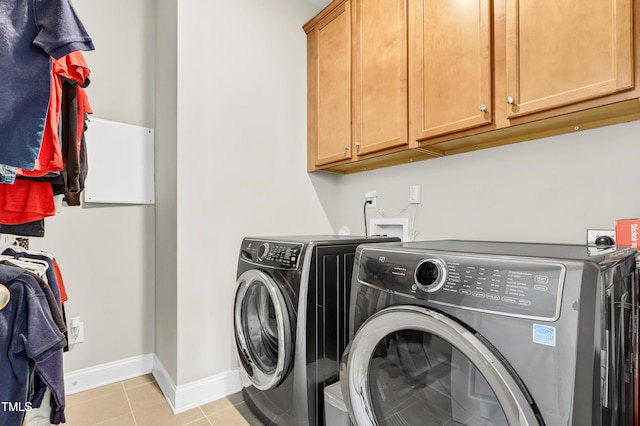 clothes washing area featuring washer and dryer, baseboards, cabinet space, and light tile patterned floors