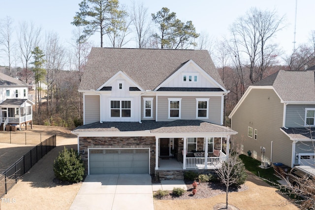 view of front of home featuring covered porch, concrete driveway, a garage, stone siding, and board and batten siding