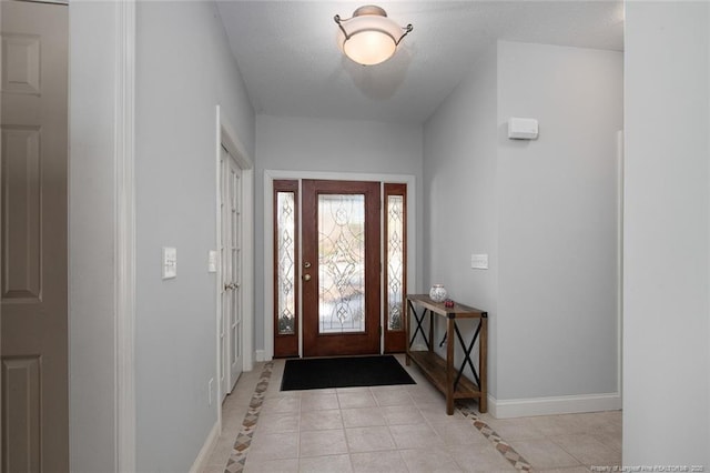 foyer entrance with light tile patterned flooring, baseboards, and a textured ceiling