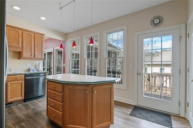 kitchen featuring a kitchen island, light countertops, dishwashing machine, dark wood-style flooring, and hanging light fixtures