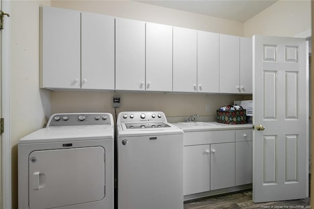 clothes washing area featuring a sink, cabinet space, dark wood finished floors, and washer and clothes dryer