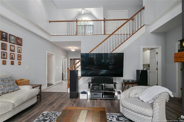 living room featuring baseboards, ceiling fan, stairway, a high ceiling, and wood finished floors