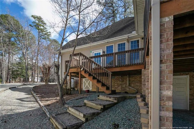 exterior space with stairway, a garage, brick siding, and roof with shingles