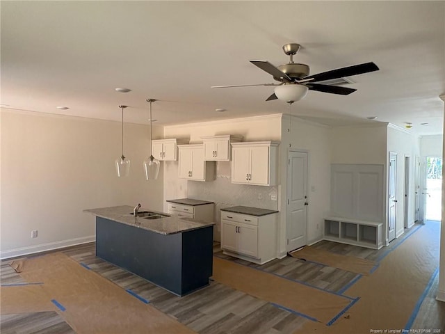 kitchen featuring white cabinetry, a sink, ceiling fan, a center island with sink, and hanging light fixtures