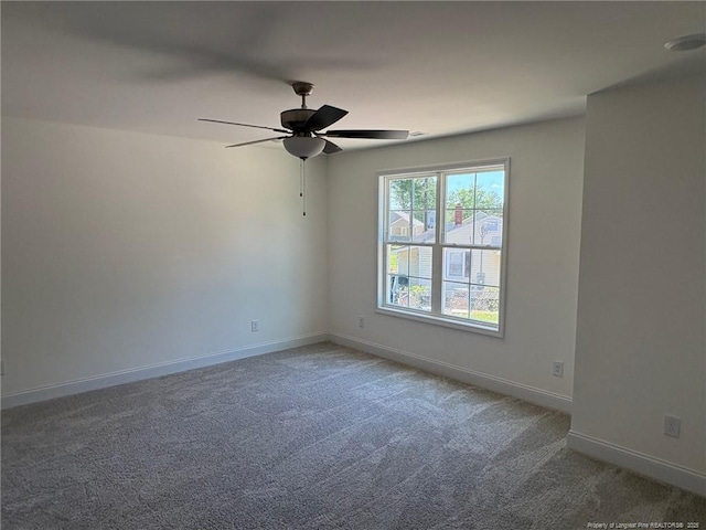 carpeted empty room featuring ceiling fan and baseboards