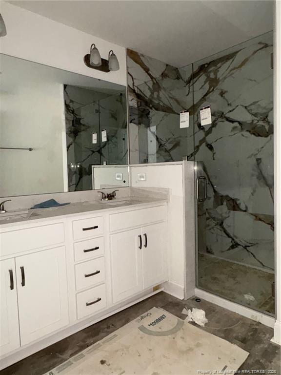 bathroom featuring a marble finish shower and double vanity