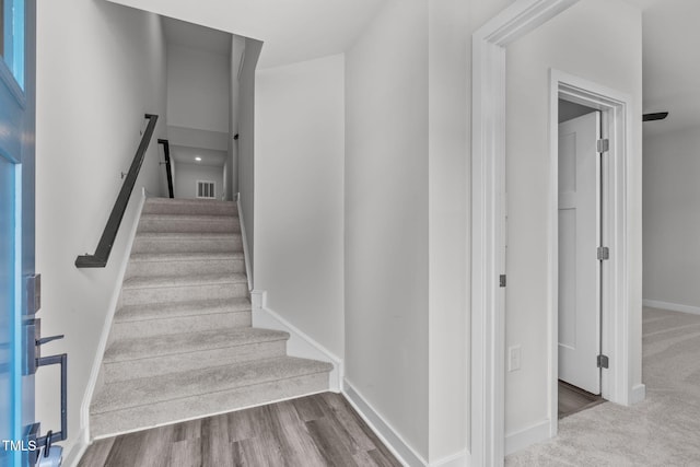 stairway featuring visible vents, baseboards, and wood finished floors