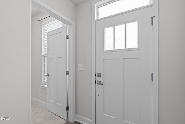 entrance foyer featuring baseboards and light colored carpet