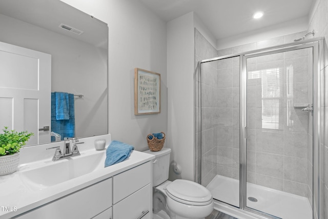 bathroom featuring vanity, toilet, visible vents, and a stall shower