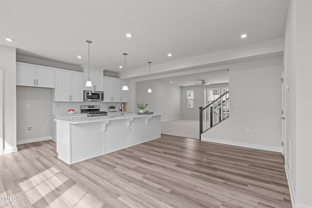 kitchen featuring open floor plan, white cabinetry, recessed lighting, appliances with stainless steel finishes, and light countertops