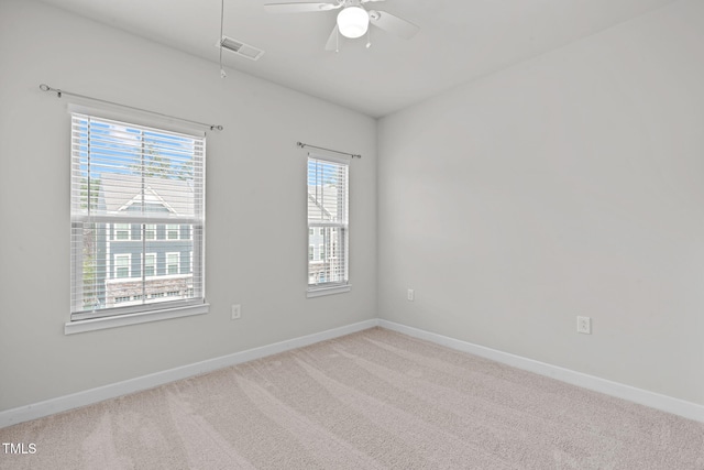 carpeted spare room featuring visible vents, baseboards, and a ceiling fan