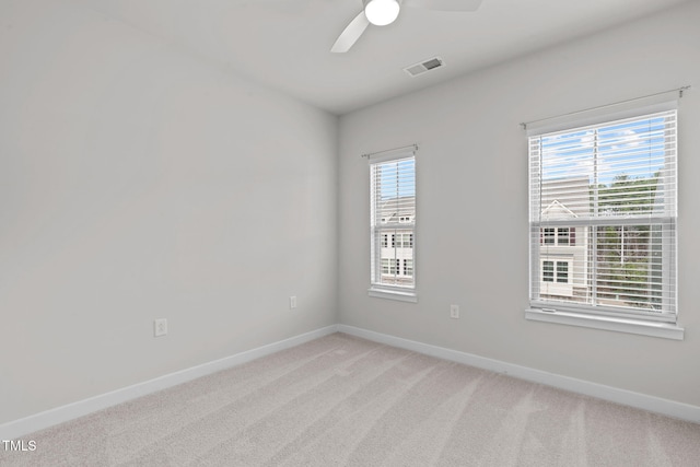 spare room with baseboards, light carpet, plenty of natural light, and visible vents