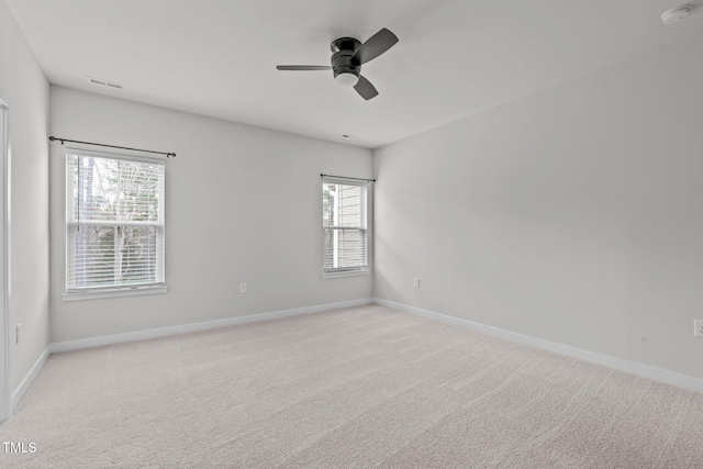 spare room featuring baseboards, light colored carpet, visible vents, and ceiling fan