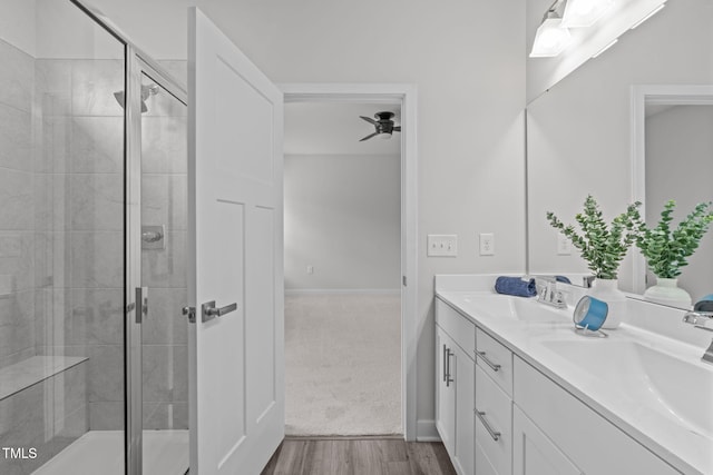 full bath with ceiling fan, a shower stall, and a sink