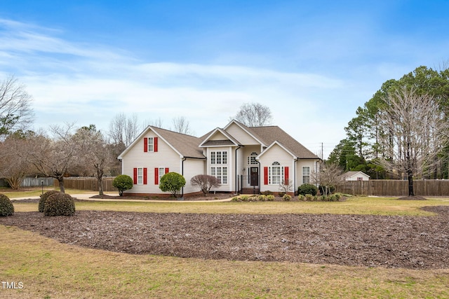 view of front facade featuring a shingled roof, a front yard, and fence