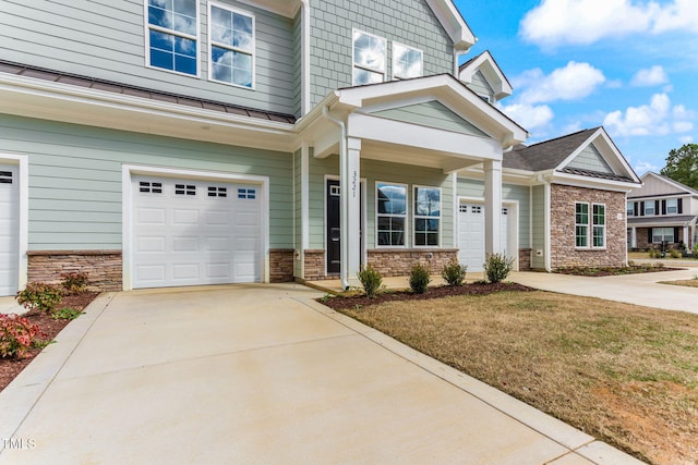 craftsman-style house featuring stone siding, a garage, driveway, and a standing seam roof