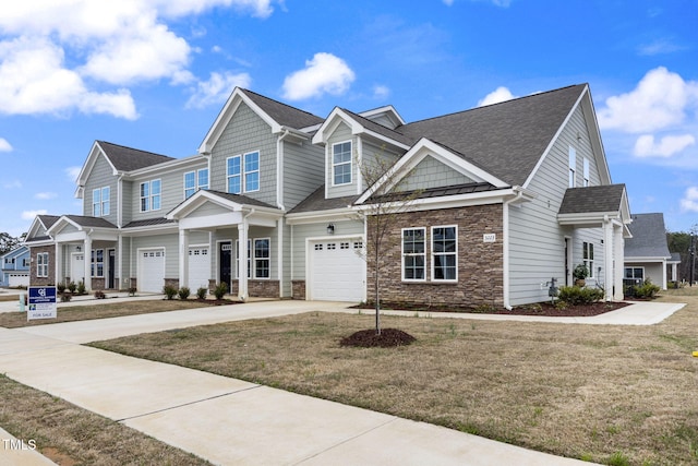 view of front facade with driveway, stone siding, a front yard, a shingled roof, and a garage