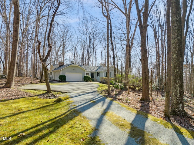 view of front of property with a chimney, driveway, an attached garage, and a front lawn