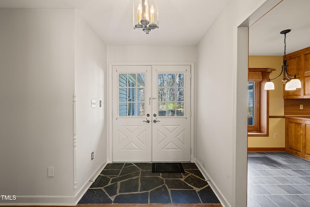 doorway featuring stone finish floor, french doors, baseboards, and a chandelier