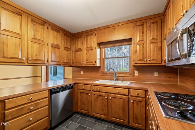 kitchen with a sink, stainless steel appliances, brown cabinets, and a peninsula