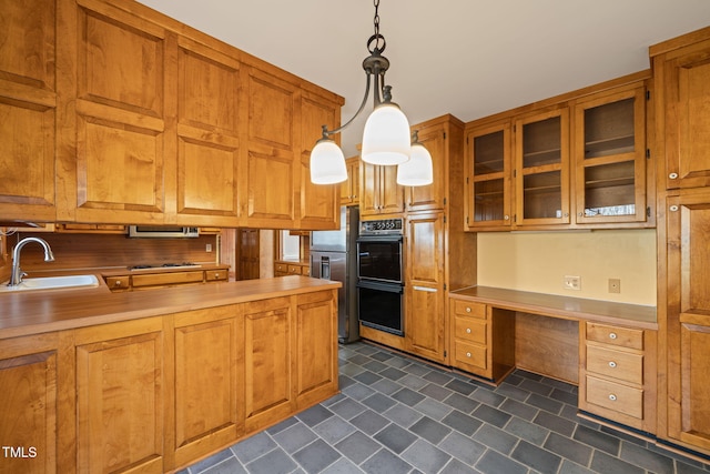 kitchen with built in study area, light countertops, brown cabinetry, and a sink