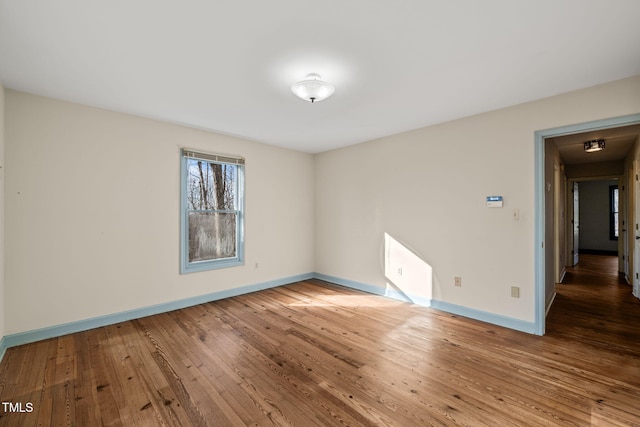 spare room featuring baseboards and hardwood / wood-style floors