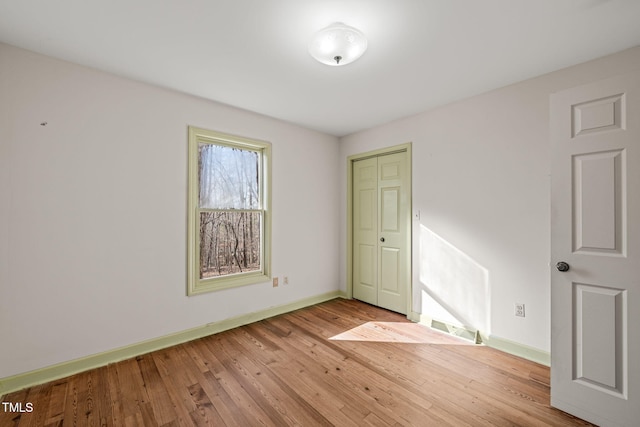 unfurnished bedroom with baseboards, light wood-type flooring, and a closet