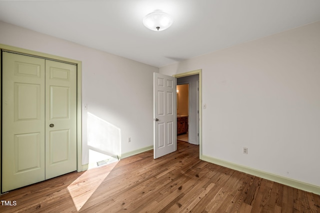 unfurnished bedroom with a closet, baseboards, and wood finished floors