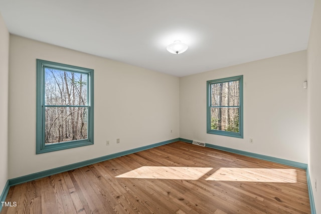 spare room featuring hardwood / wood-style floors, baseboards, and visible vents