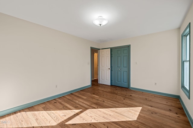 spare room with baseboards and wood finished floors