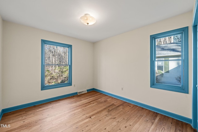 spare room with light wood finished floors, visible vents, and a wealth of natural light