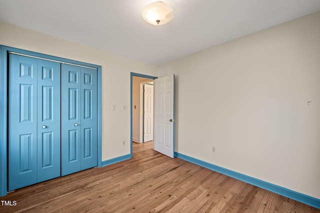 unfurnished bedroom featuring baseboards, light wood-type flooring, and a closet