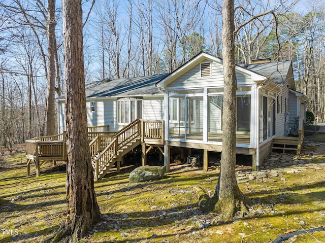 back of house with stairway, a wooden deck, roof with shingles, and a sunroom