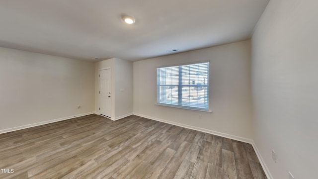 empty room with visible vents, baseboards, and wood finished floors