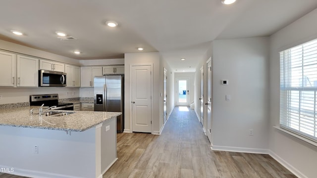 kitchen with a sink, stainless steel appliances, plenty of natural light, and light wood-style floors