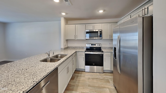 kitchen featuring a sink, visible vents, light stone countertops, and appliances with stainless steel finishes