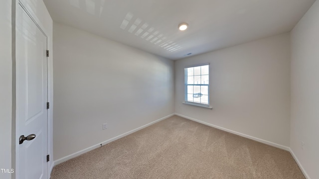 spare room featuring visible vents, baseboards, and light colored carpet