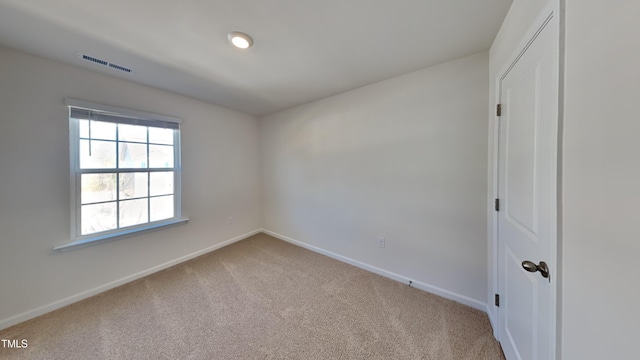 carpeted spare room featuring visible vents and baseboards